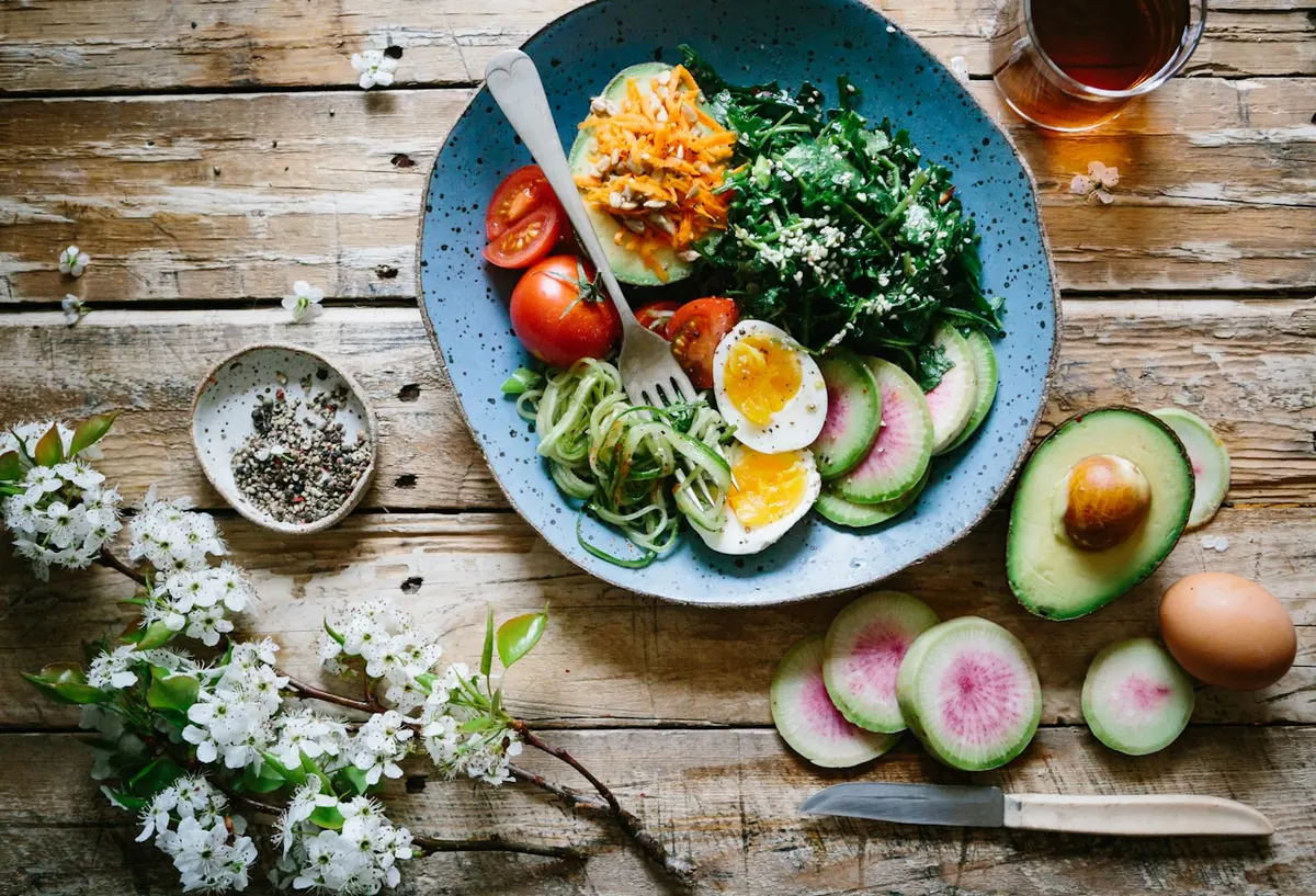 Balanced bowl with greens, egg, avocado and fresh vegetables