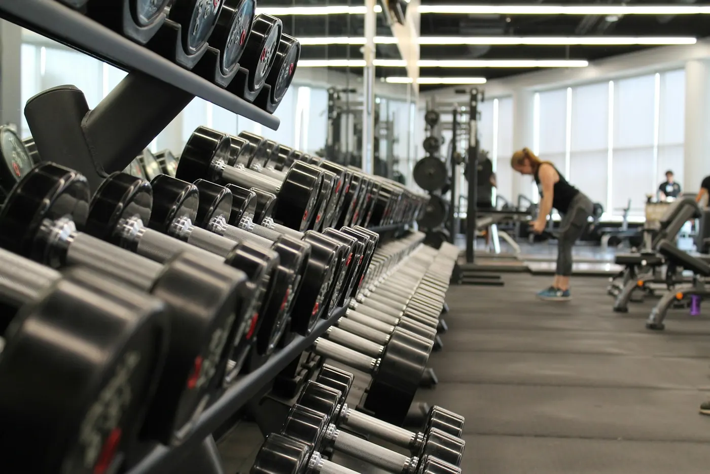 Gym floor with weights and soft-focus people training in the background